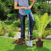 Person using the Gardena Teraline Spade with D grip to dig a hole in a garden, preparing to plant a fern beside a pond surrounded by flowers and greenery.