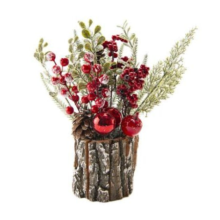 A Christmas artificial floral arrangement in a faux bark pot, featuring red berries, green pine branches, frosted greenery, and red ornaments on a white background.