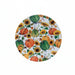 A round white plate with a colorful autumn harvest pattern featuring pumpkins, gourds, sunflowers, and leaves.