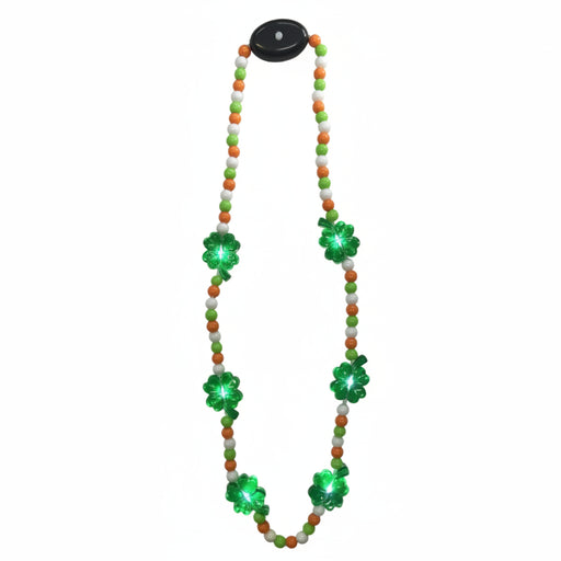 A beaded necklace with green and orange beads and a black pendant featuring a four leaf clover design. The beads are adorned with small green LED lights.