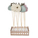 A decorative autumn-themed display featuring five hand-painted wooden pumpkins in pastel colors (cream, mint green, teal, and pink) with dark brown stems, mounted on wooden sticks over a small light wood picket fence base filled with white faux snow.