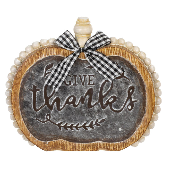 A decorative pumpkin-shaped sign with a faux chalkboard center reading “GIVE thanks,” a wooden-look border, a bead-like edge, and a black-and-white gingham bow at the top, shown on a white background.