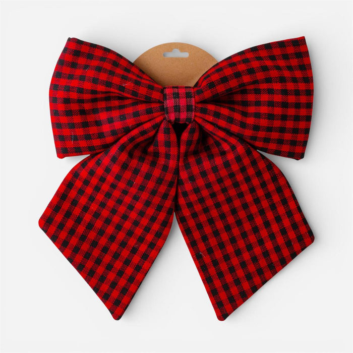 A large fabric bow in a red and black buffalo plaid pattern, attached to a brown cardboard hanger against a light gray background.