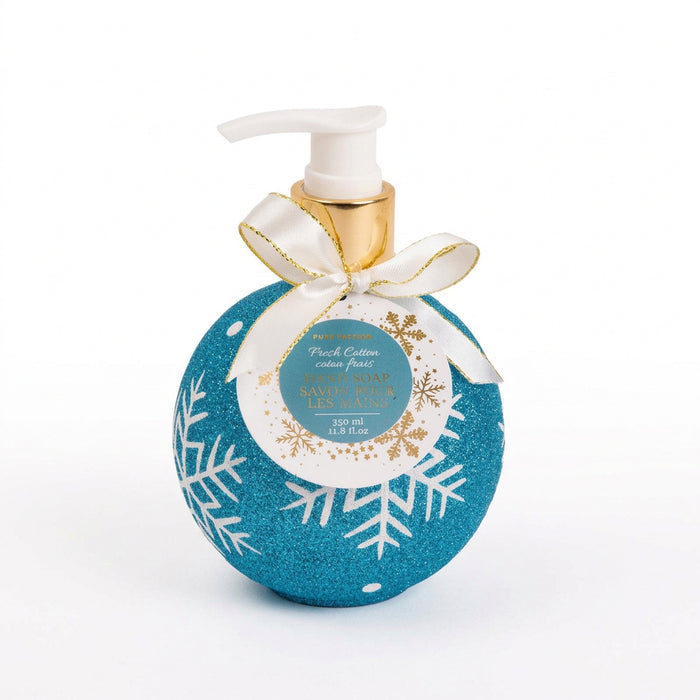 A festive holiday-themed hand soap bottle with a glittery blue body, white snowflake patterns, a white pump dispenser, and a white ribbon with gold trim tied around the neck.