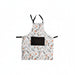 A white kitchen apron with a black neck strap and waist ties, featuring an all-over botanical pattern of orange berries, pinecones, and gray leaves. It has a large black rectangular pocket on the front.