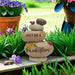 Decorative stone stack with 'Just Be A Wildflower' text in a garden setting