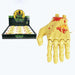 Halloween wind-up toy hand candy shown next to its retail display box. The hand is flesh-toned with red blood splatter details, and the box features a black background with a yellow moon graphic and 'Happy Halloween Wind-Up Toy' text.