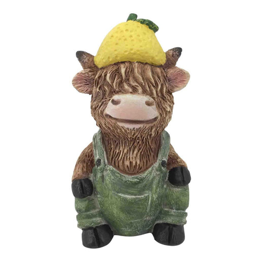 Statue of a cow wearing green overalls and a yellow hat on a white background