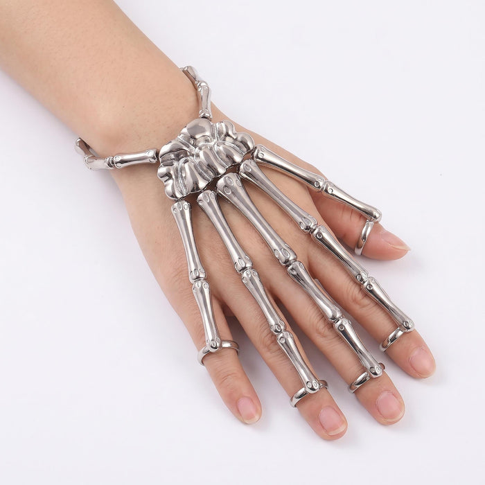 A silver metallic skeletal hand ring worn on a person's hand, featuring detailed bone structures on each finger and a wrist strap, shown against a plain white background.