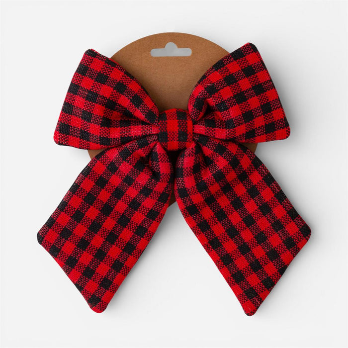 A red and black buffalo plaid fabric bow attached to a brown cardboard display hanger, photographed against a clean white background.