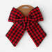 A red and black buffalo plaid fabric bow attached to a brown cardboard display hanger, photographed against a clean white background.