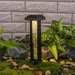 Garden light fixture with decorative stones and plants against a brick wall.
