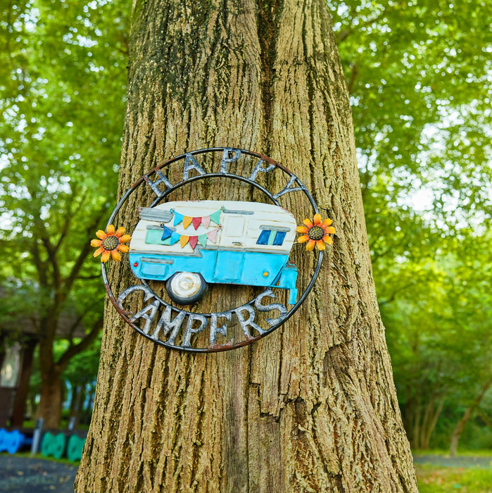Decorative sign with 'Happy Campers' and a camper design on a tree trunk.