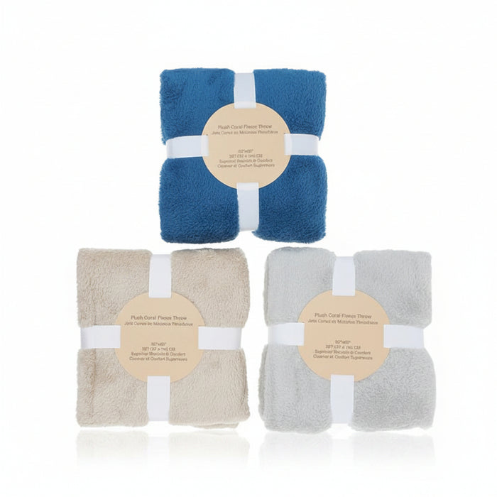 Three folded plush towels in blue, beige, and light gray, each wrapped with a white band and a round beige label, arranged on a white background.