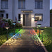 Solar-powered garden lights casting colorful patterns on a pathway in front of a house.