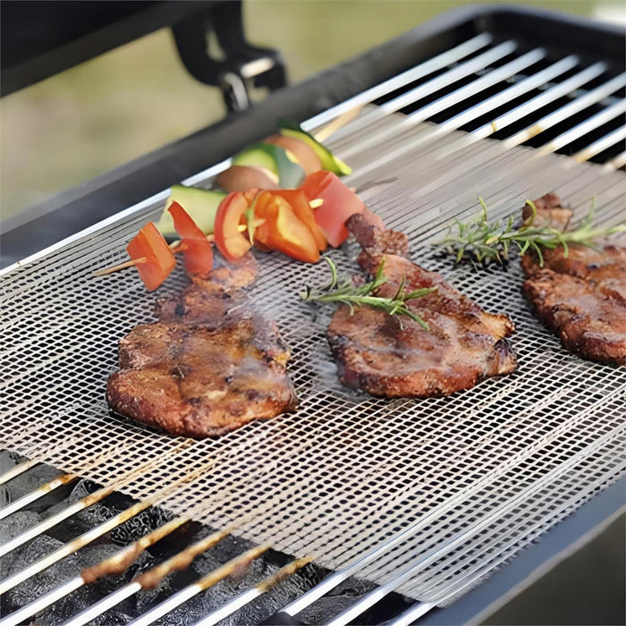 Grilling meat and vegetables on a barbecue with a mesh grill mat.