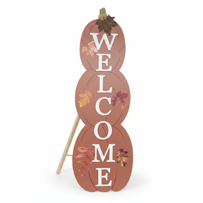 A decorative freestanding sign shaped like three stacked autumn pumpkins on a white background. The sign reads “WELCOME” in large white letters, with small fall leaf illustrations and a small hanging loop at the top.