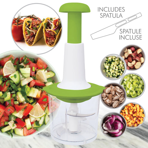 Vegetable chopper with green handle and white body, surrounded by chopped vegetables and a taco.