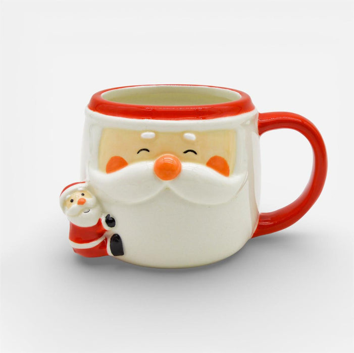 A ceramic Santa Claus mug with a red handle, red rim, and a small Santa figure peeking out from the side, shown on a light gray background.