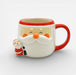 A ceramic Santa Claus mug with a red handle, red rim, and a small Santa figure peeking out from the side, shown on a light gray background.