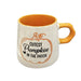 A ceramic mug with a speckled off-white exterior, a bright orange interior and handle, and a printed pumpkin graphic with the text 'Cutest Pumpkin in the Patch'.