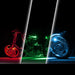 Three views of a motorcycle wheel and body illuminated by colored LED light strips in red, green, and blue, set against a black background with white diagonal divider lines.