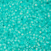 Turquoise glass beads of various sizes on a textured surface