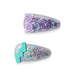 Two colorful children’s hair clips filled with glittery star-shaped confetti. The top clip has purple stars with a lavender sunglasses decoration on one end, and the bottom clip has multicolored pastel stars with a teal zig-zag design on one end.