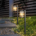 Two outdoor garden lights on grass with a blurred background