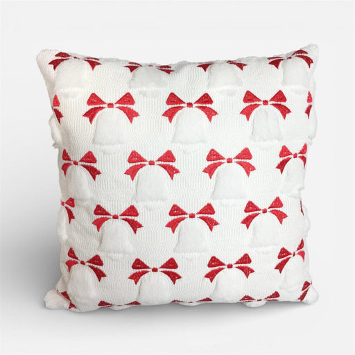 A square white textured throw pillow featuring a repeating pattern of red glittery bows, shown against a light gray studio background.