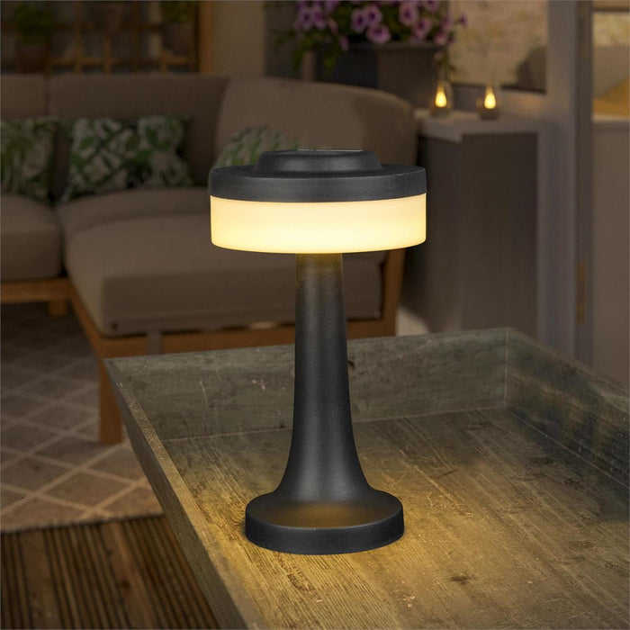 Black outdoor lamp on a wooden table with a blurred background