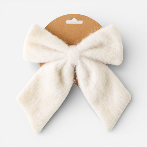 A fluffy cream-colored bow accessory attached to a brown cardboard hanger, shown against a light gray background.
