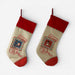 Two Christmas stockings with red cuffs and heels, beige bodies, and red-and-green striped trim, each printed with holiday postmark graphics and the words 'Air Mail' and 'Dec. 25'.