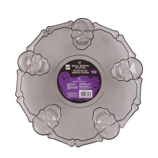 A Halloween-themed plastic serving platter shaped like a skull with decorative skull and bone motifs around the rim, featuring a purple and black center label.