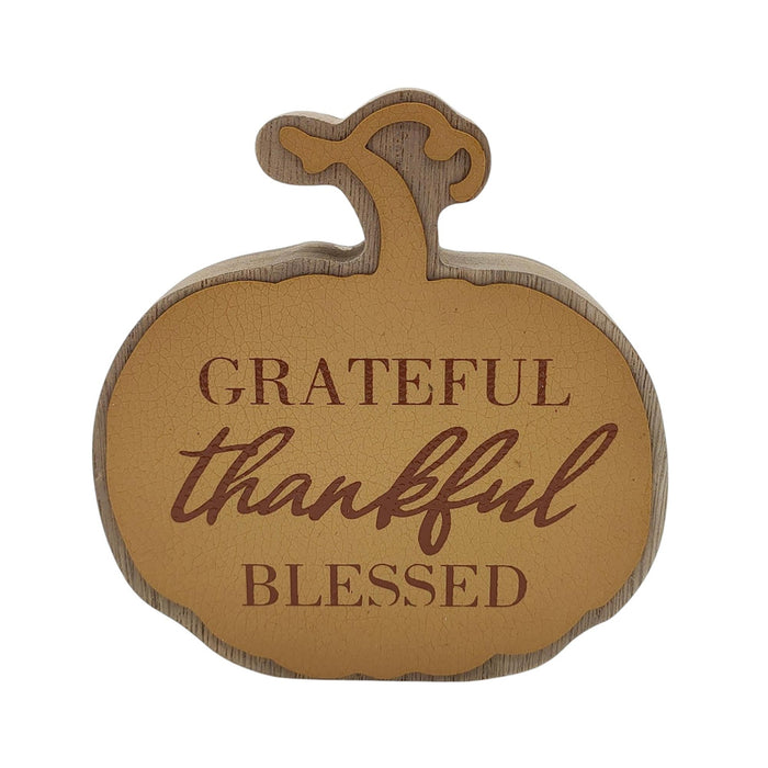A decorative wooden pumpkin-shaped sign with the words 'GRATEFUL thankful BLESSED' in brown lettering, shown on a plain white background.