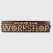 Wooden sign with 'Dad's Workshop' text and mechanical symbols on a white background