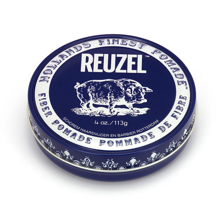 A round blue tin of Reuzel Hair Pomade on a clean white background, featuring a white illustration of a pig and the brand name 'REUZEL' in bold white letters.
