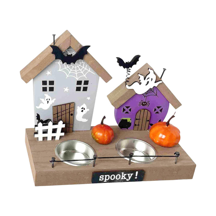 A Halloween-themed double pet feeder shaped like two houses on a wooden base. The left house is light gray with white ghosts, a black bat, and a white picket fence, while the right house is purple with white ghosts, a black cat, a spider, and a black bat.
