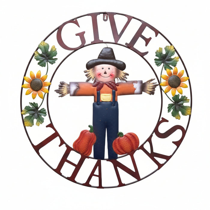 A circular autumn-themed sign with the words 'GIVE THANKS' in dark red lettering, surrounding a scarecrow, sunflowers, green leaves, and red pumpkins on a white background.