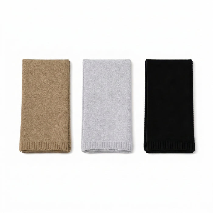 Three folded knit scarves in tan, light gray, and black, arranged side by side on a plain white background.