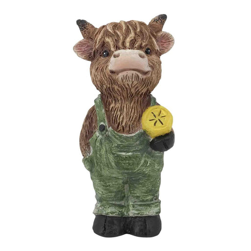 Statue of a cow wearing overalls and holding a yellow object on a white background