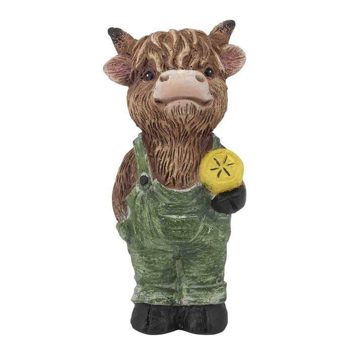 Statue of a cow wearing overalls and holding a yellow object on a white background