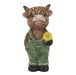 Statue of a cow wearing overalls and holding a yellow object on a white background