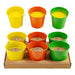 Set of colorful metal buckets with candles inside, displayed on a white background.