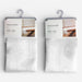 Two packaged table runners hanging on gray plastic hangers against a light gray background. Each package contains a folded white table runner with a subtle snowflake pattern and a printed header card labeled 'TABLE RUNNER' with 'STACK' and size details.
