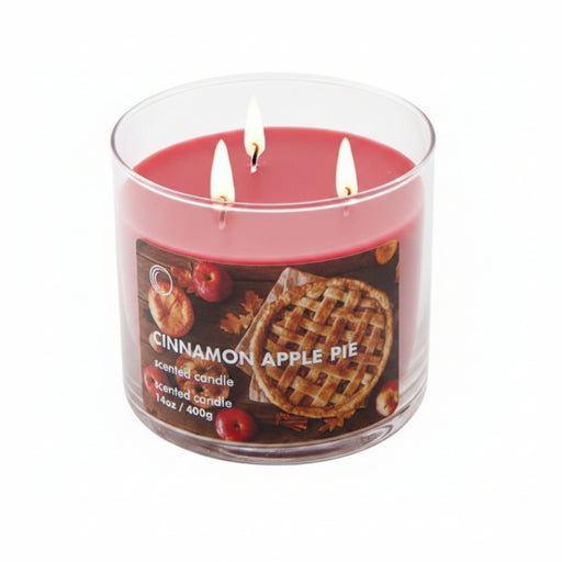 A three-wick scented candle in a clear glass jar with red wax, shown with its lid leaning against the jar on a white background. The front label reads 'cinnamon apple pie' and features a waffle graphic.