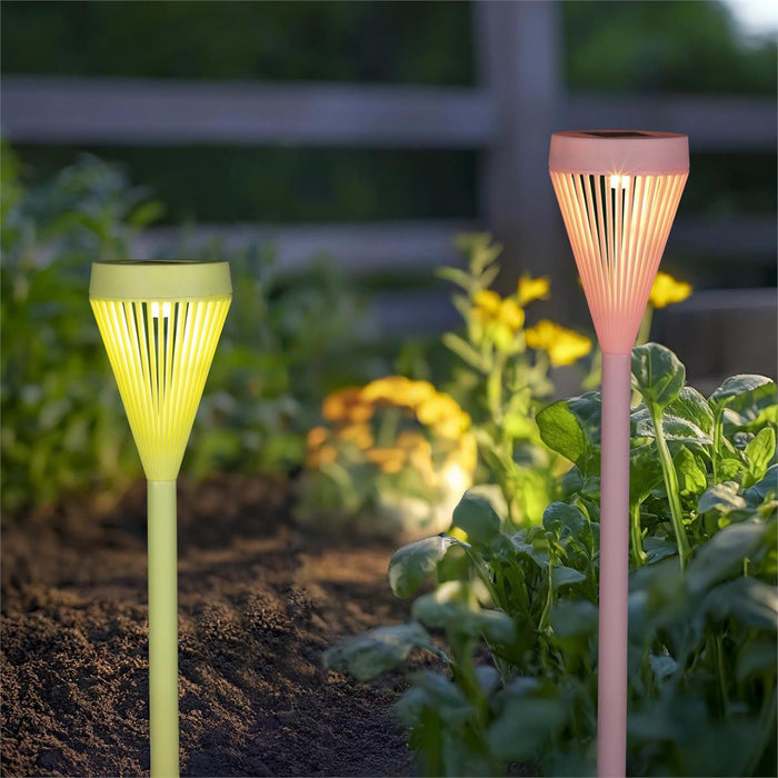 Two solar garden lights, one green and one pink, in a garden setting with plants and flowers.